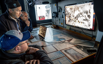 Three people looking at a computer screen.